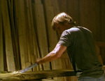 Clay works in his shop, planing boards that will be used to make coffins. (Viggo Mortensen)